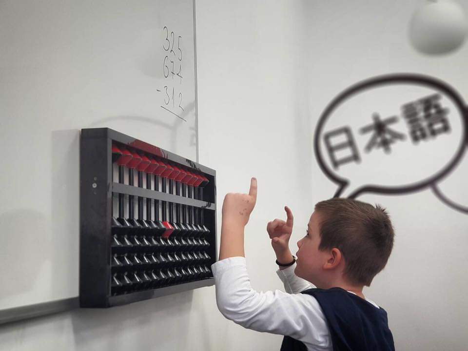 Kind leert rekenen met telraam (abacus) in klaslokaal.